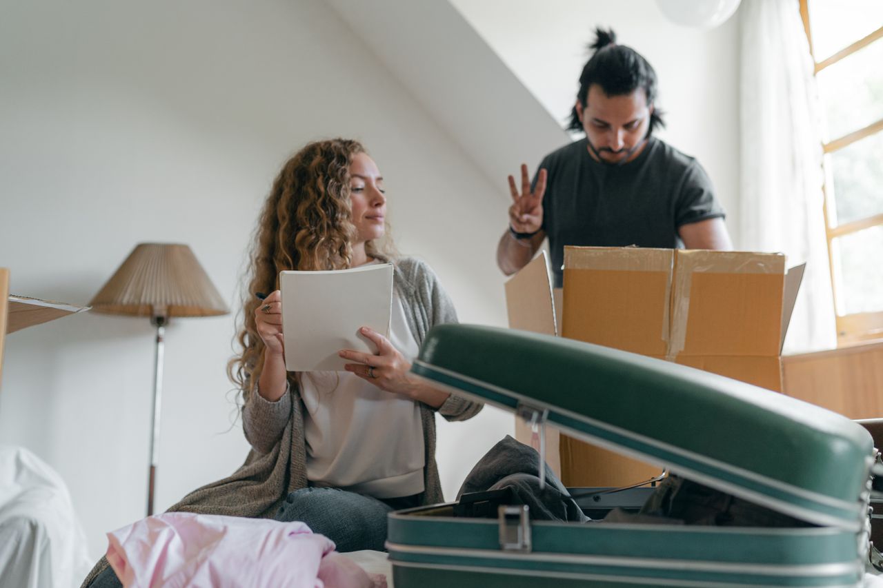 Crafting Captivating Headlines: Your awesome post title goes here Positive concentrated couple counting belonging and taking notes while packing stuff into carton boxes and suitcases near window in sunny bedroom