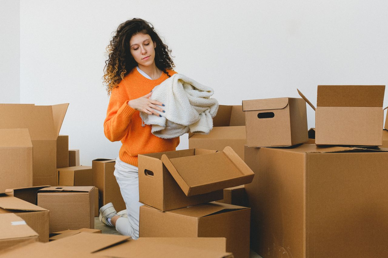 The Art of Drawing Readers In: Your attractive post title goes here Concentrated young lady with curly hair standing on knees on floor and packing clothes into carton boxes before moving into new flat